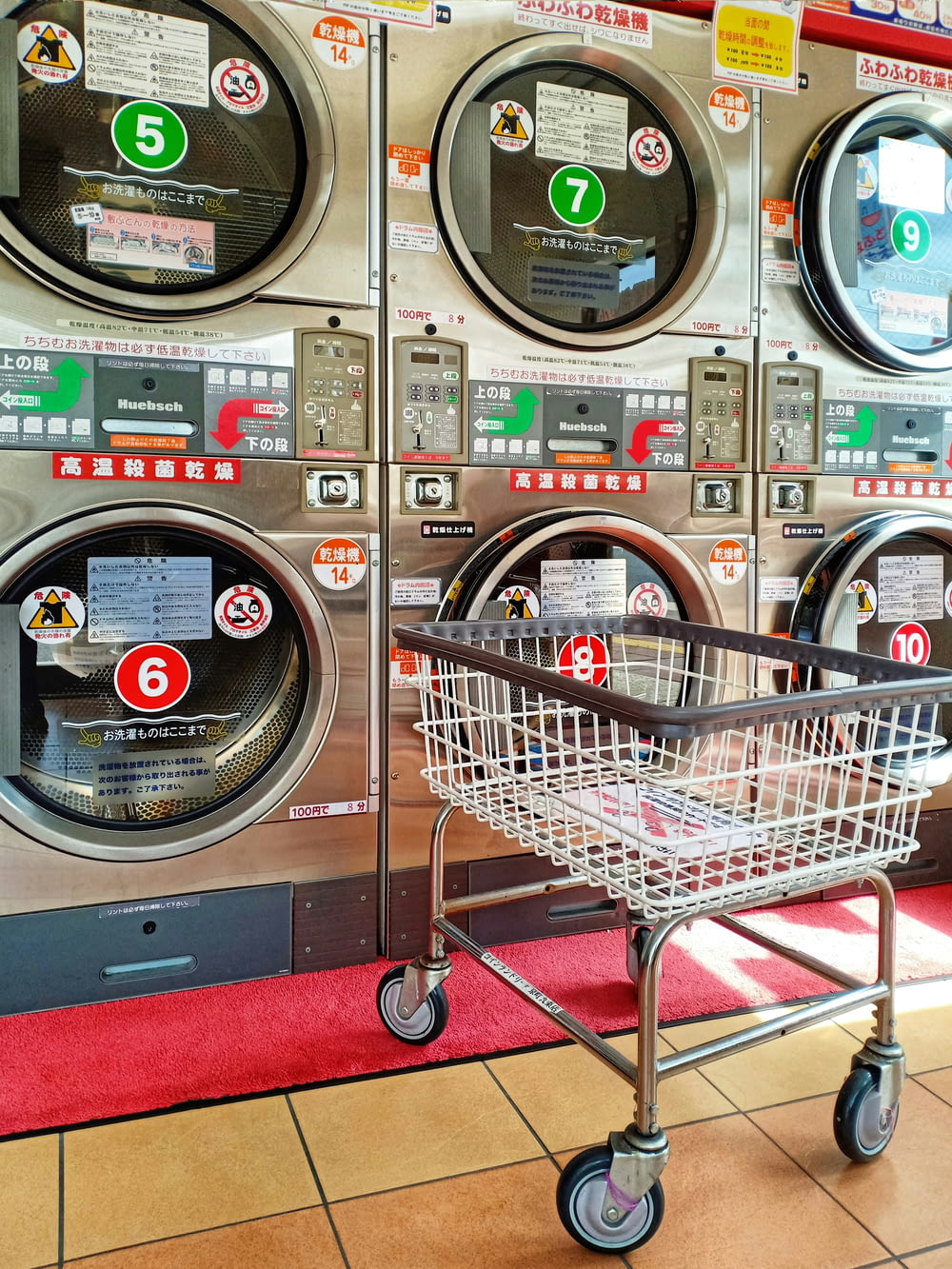 Un carrito de compras frente a una fila de lavadoras
