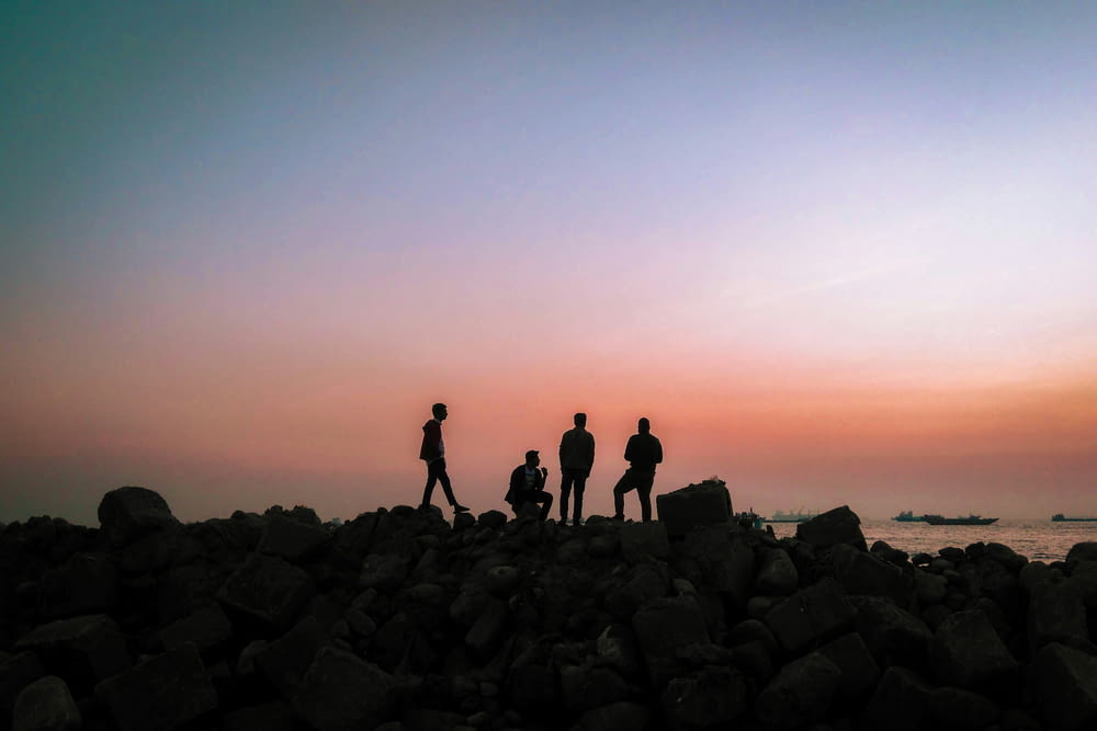 a group of people standing on top of a rocky beach