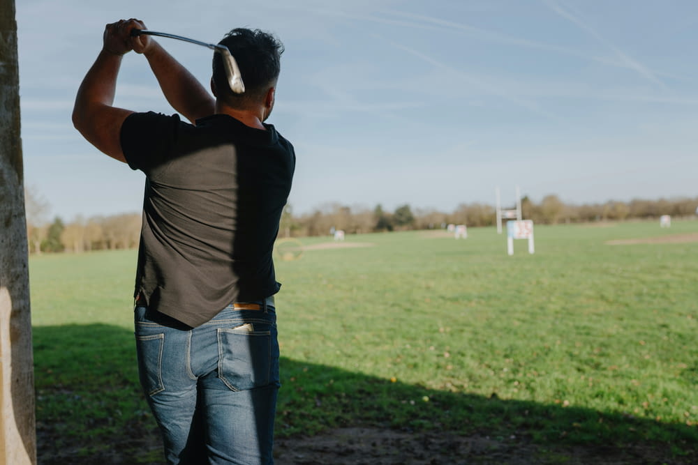 a man swinging a golf club in a field