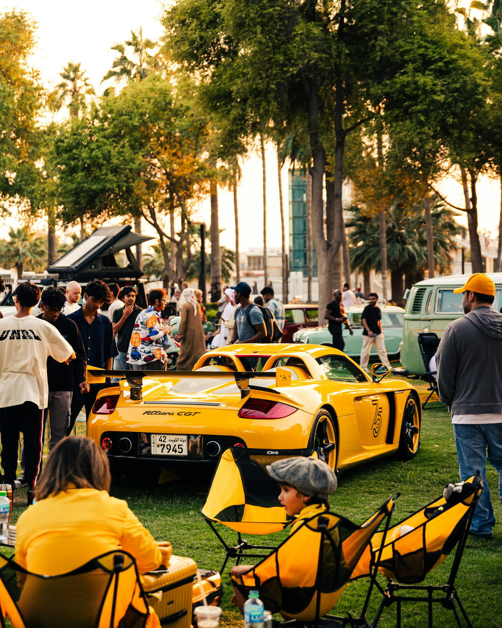 a group of people standing around a yellow race car