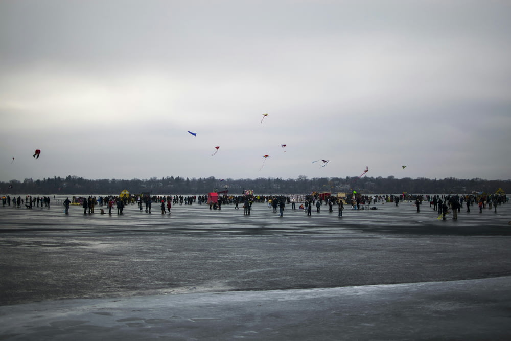 a group of people flying kites on top of a frozen lake