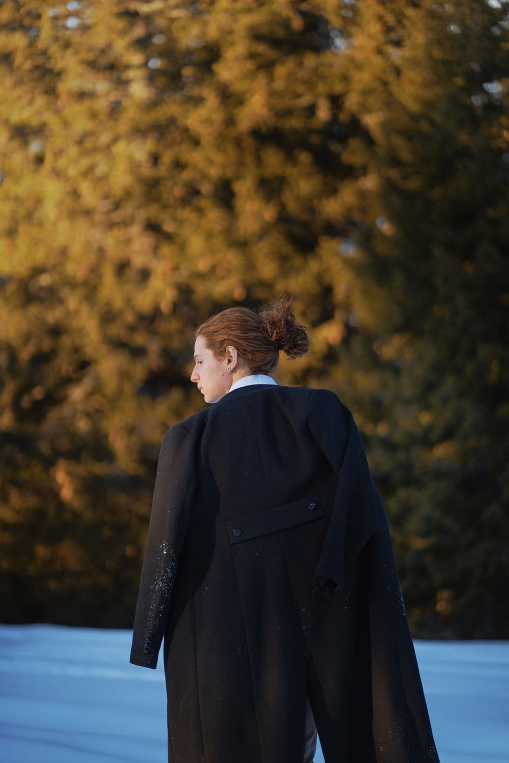 a woman in a black coat walking in the snow