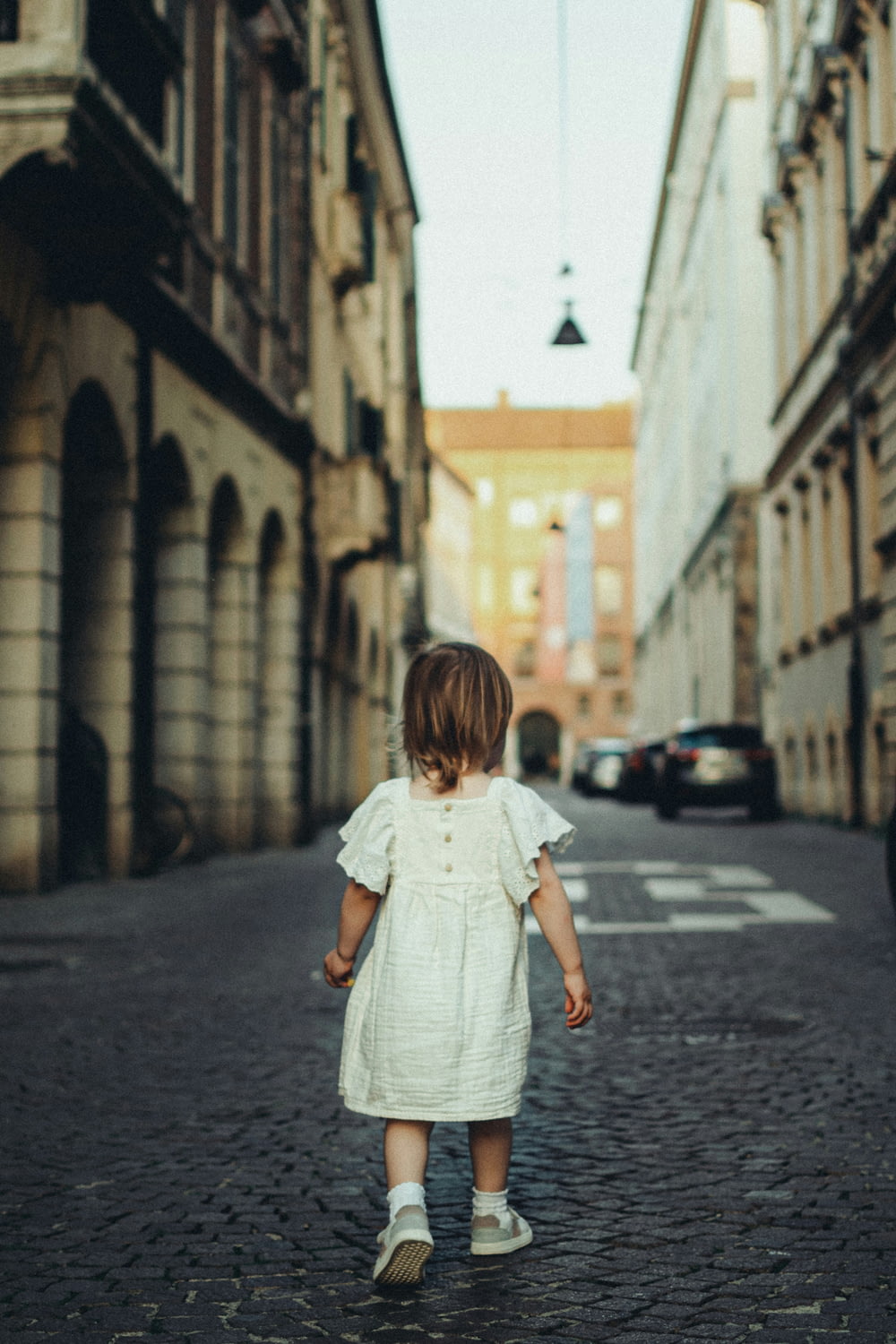 a little girl walking down a cobblestone street