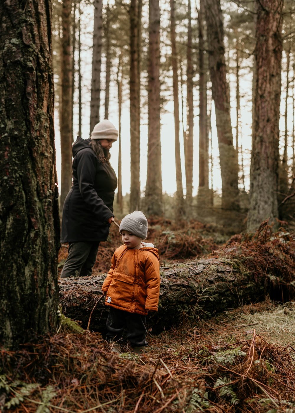 a man standing next to a little boy in a forest