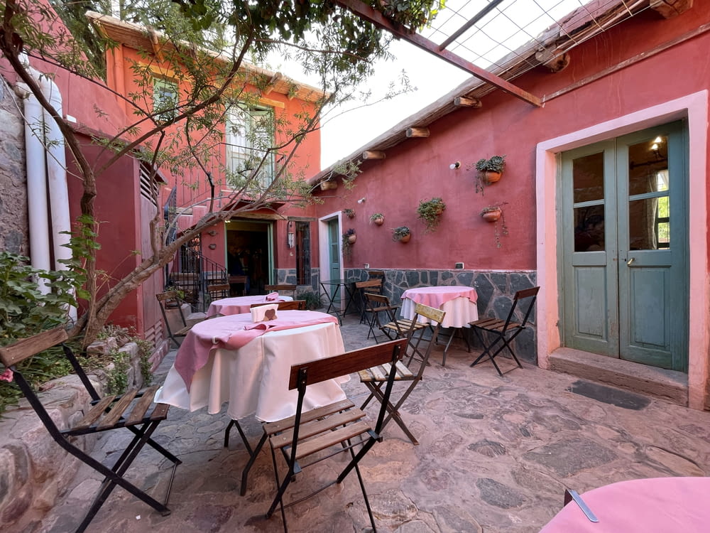 a patio with tables and chairs and a pink wall