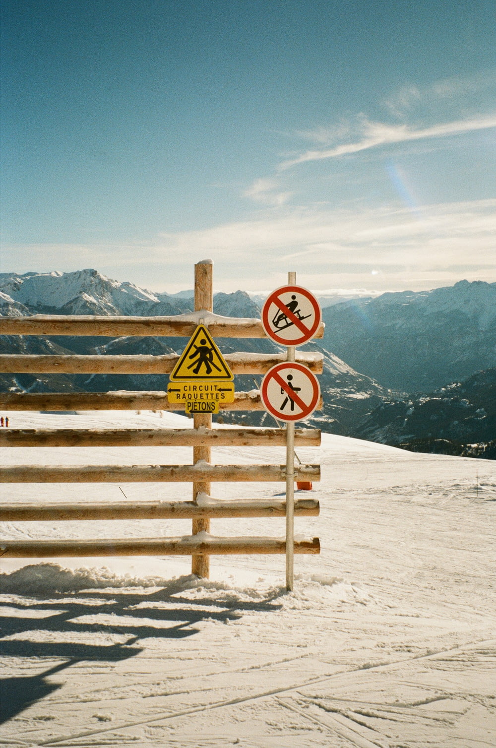 a group of signs on a wooden fence in the snow