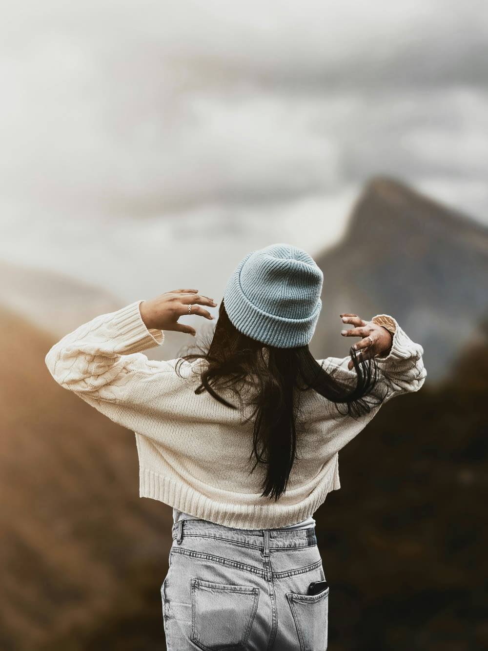 a woman wearing a blue hat standing in front of a mountain