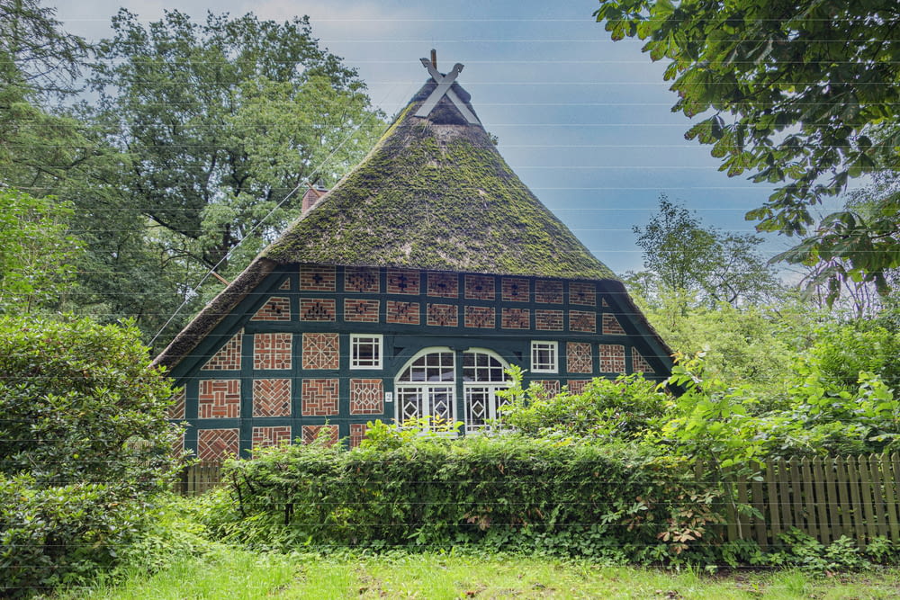 a small house with a thatched roof in the woods