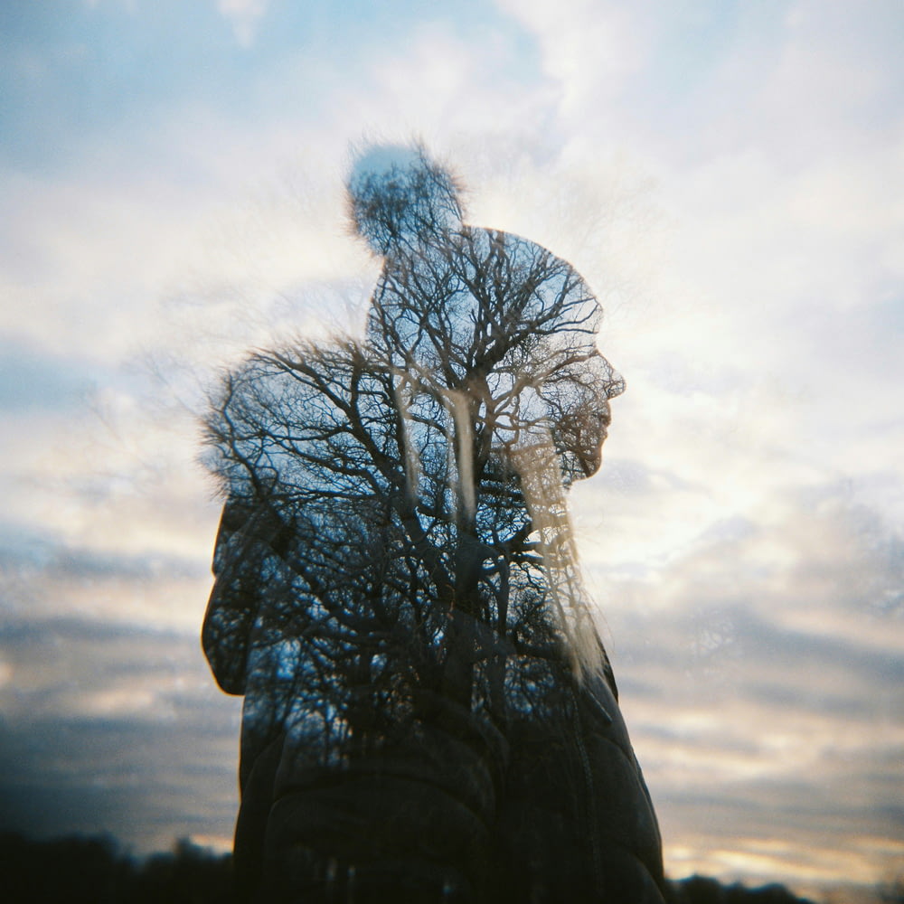 un riflesso di una persona con alberi sullo sfondo