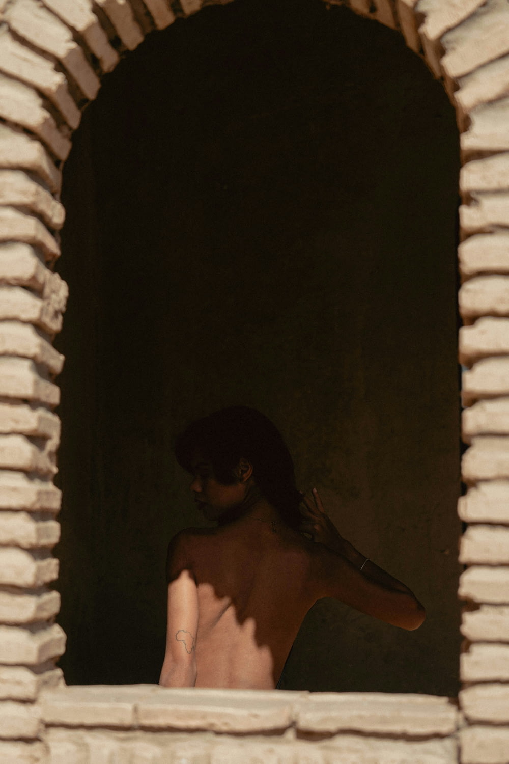 a woman with no shirt standing in a window