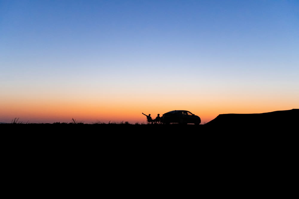 a silhouette of a person standing in front of a car