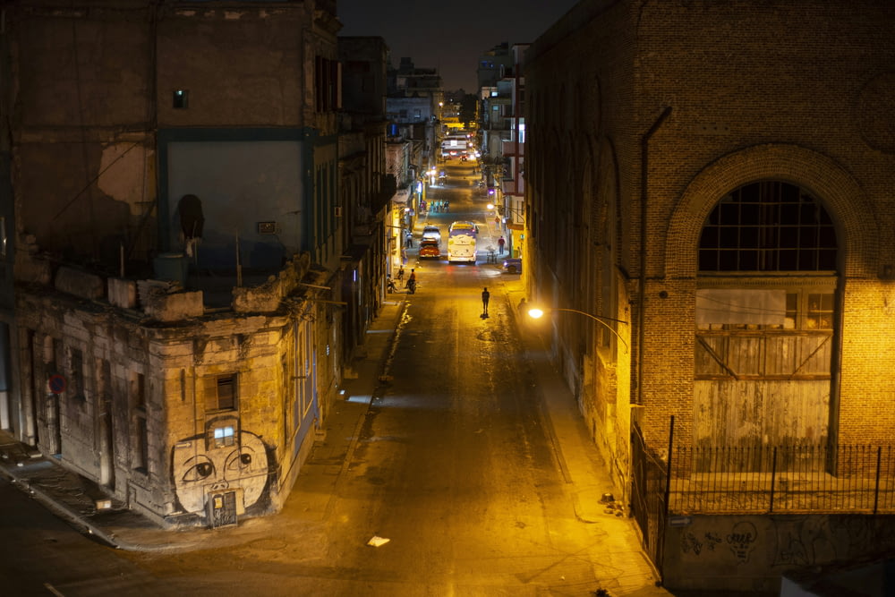 uma rua da cidade à noite com uma pessoa andando pela rua