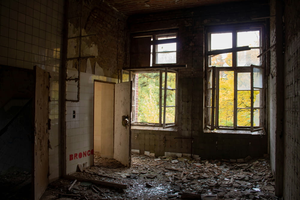 a run down room with broken windows and debris on the floor