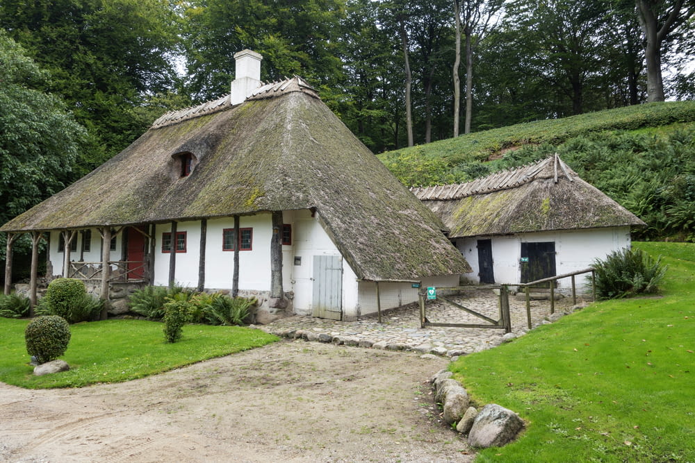 a white house with a thatched roof in a park