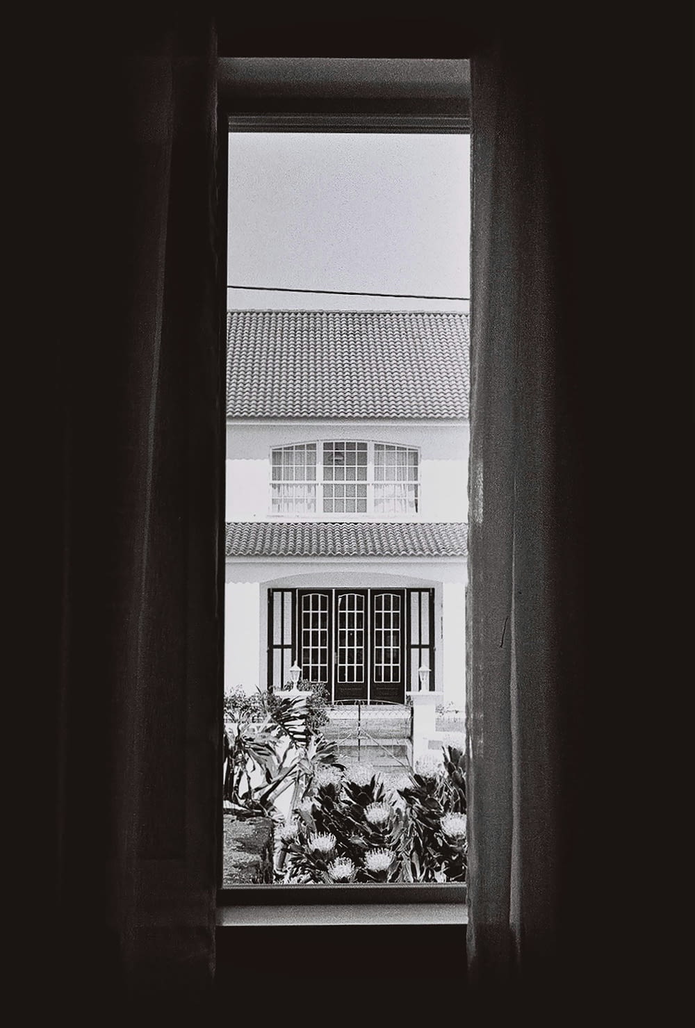 ein Schwarz-Weiß-Foto eines Hauses durch ein Fenster