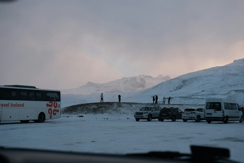 a group of cars parked in a parking lot next to a snow covered mountain