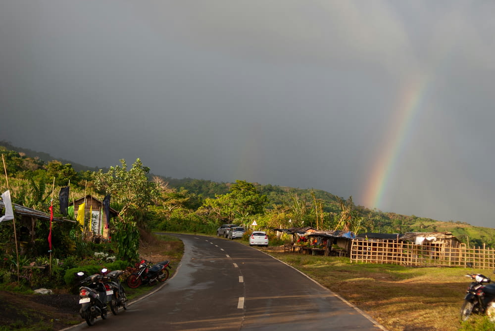 a rainbow in the sky over a rural road
