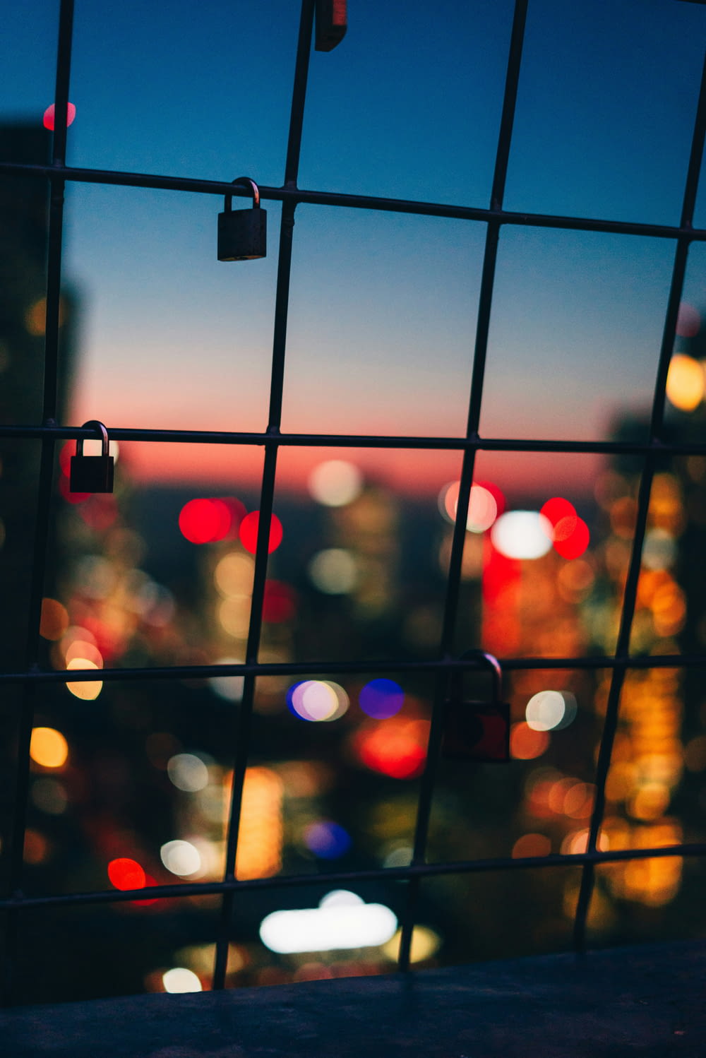 a view of a city at night through a fence