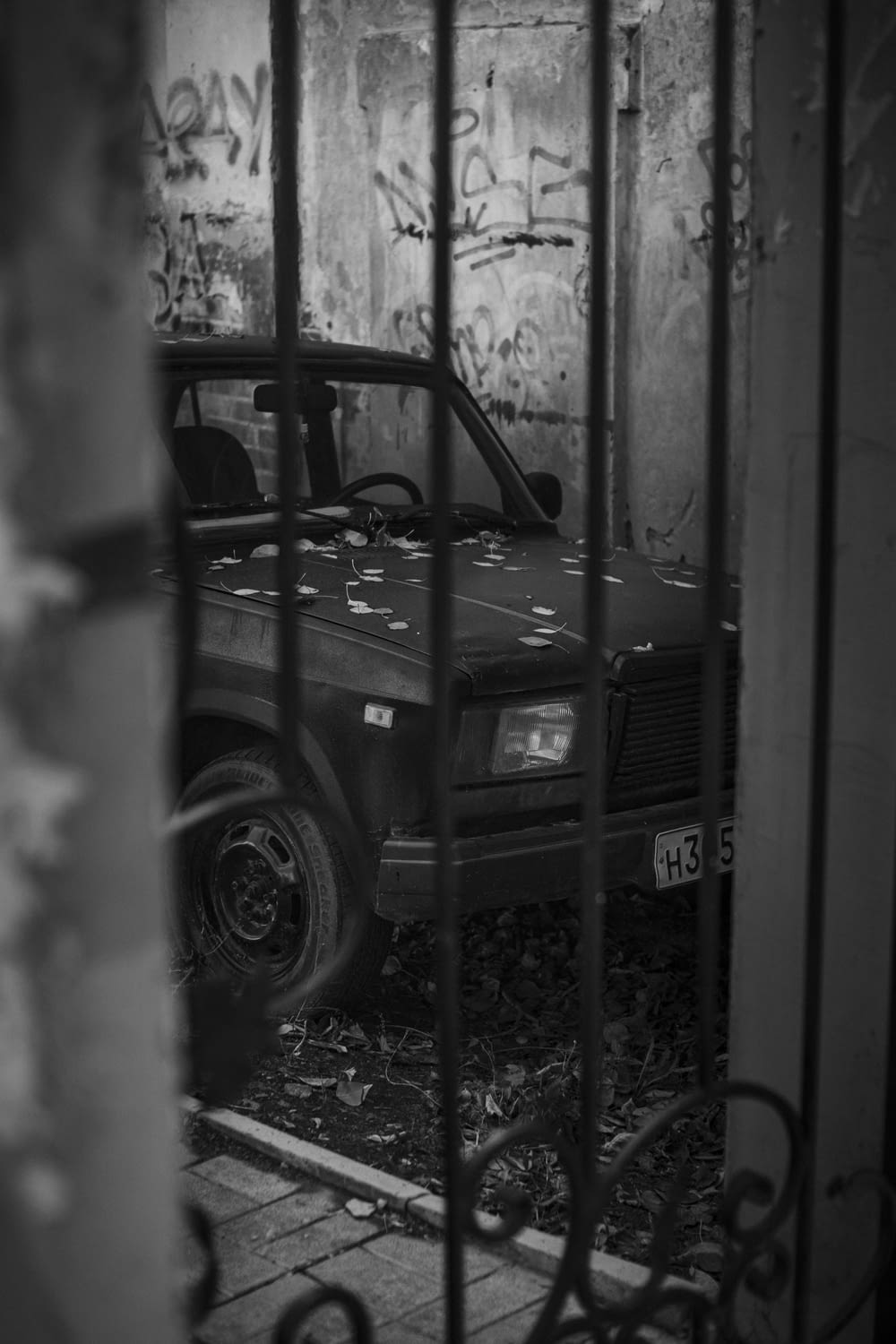 a black and white photo of a car behind a fence