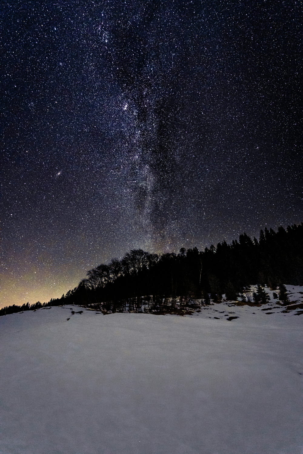 the night sky is filled with stars above a snowy field