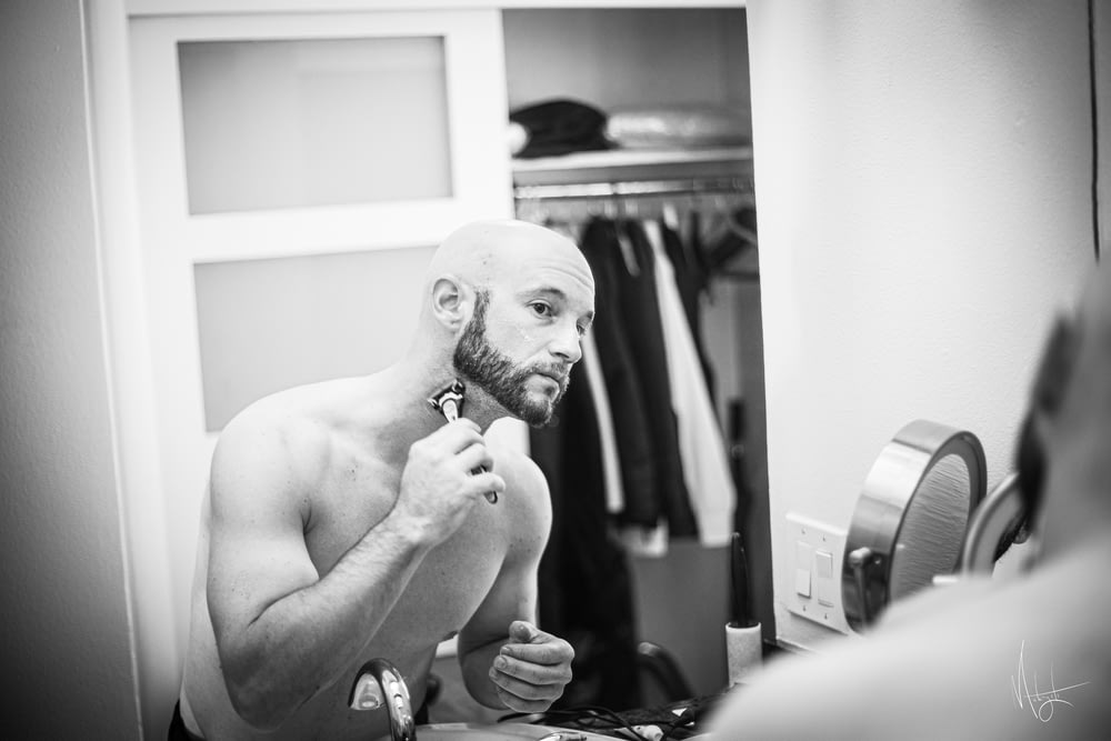 a shirtless man brushing his teeth in front of a mirror