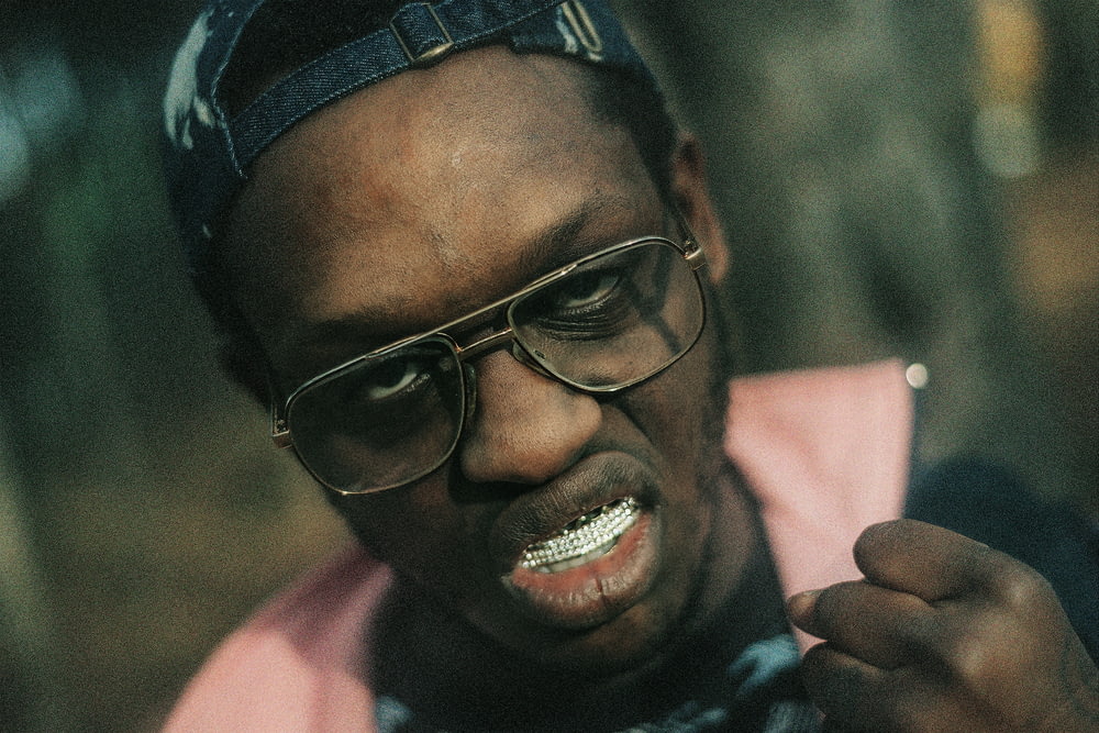 a man wearing glasses and a hat with a toothbrush in his mouth