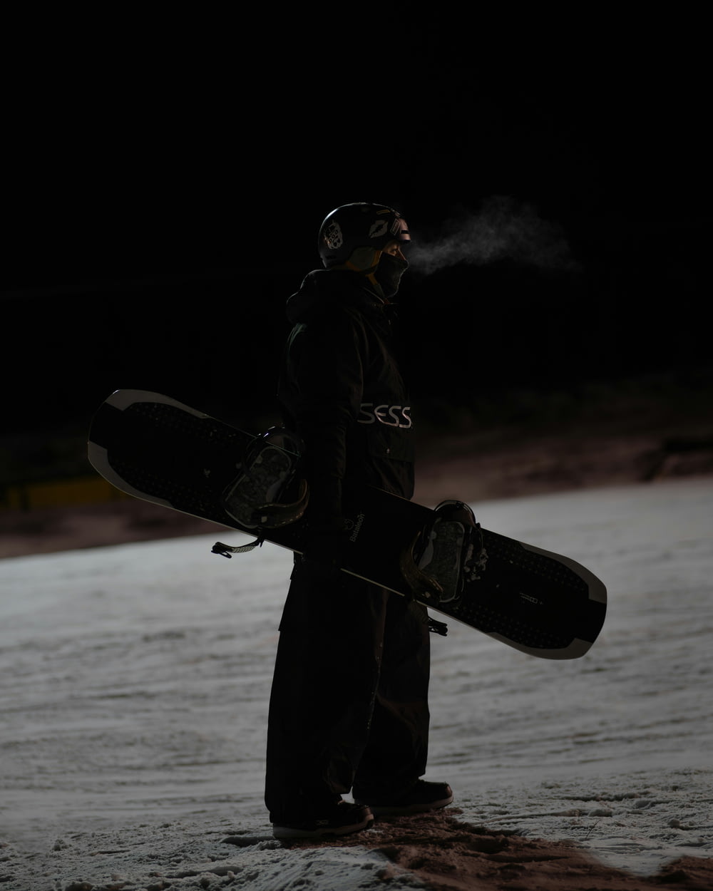 a man standing in the snow holding a snowboard
