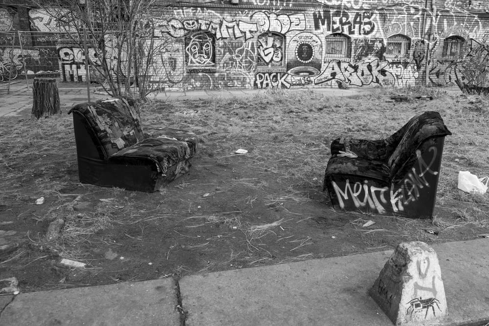 a black and white photo of two couches in front of a graffiti covered wall