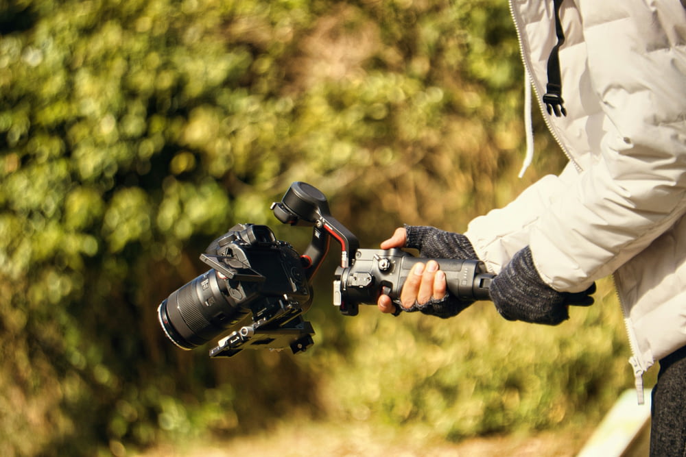 una persona sosteniendo una cámara y un trípode