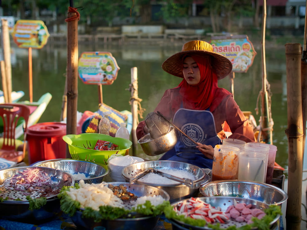 a woman in a hat is selling food on a boat