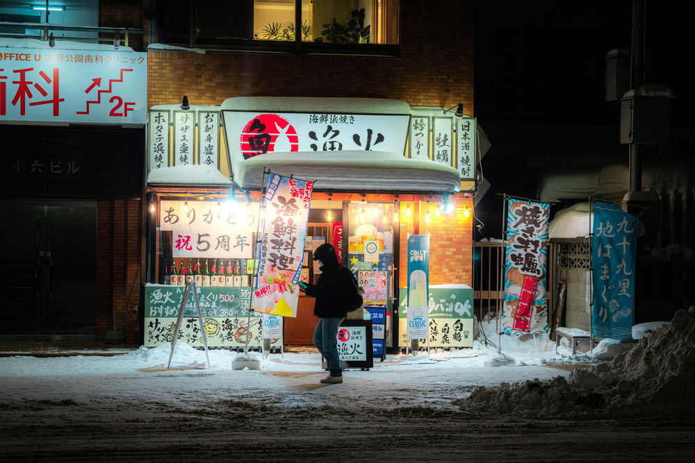 a woman standing in front of a store at night