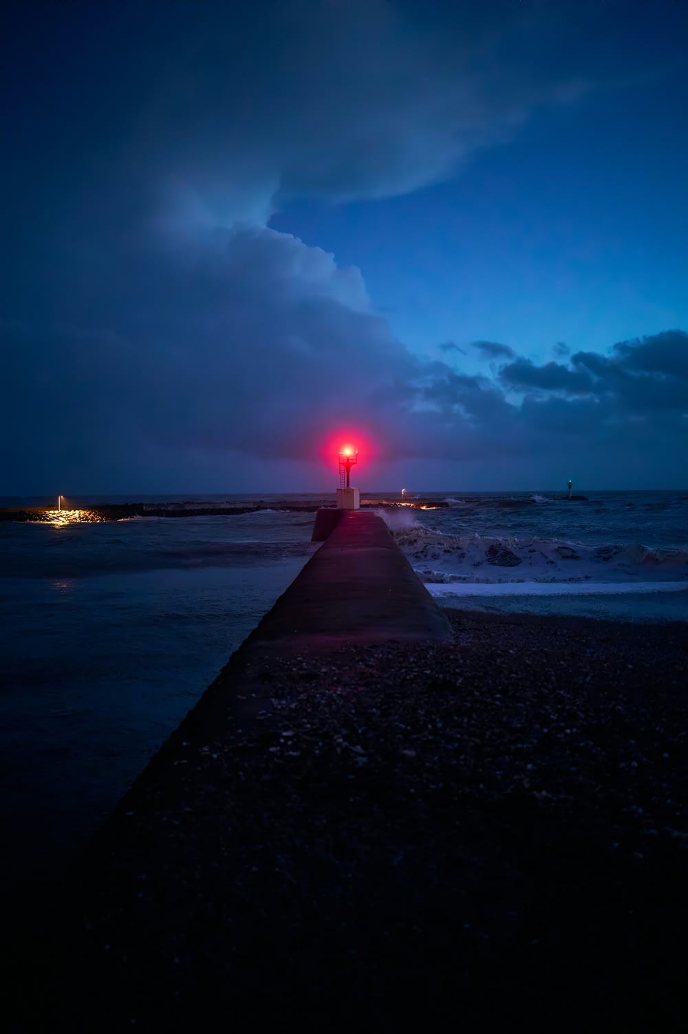 a red light at the end of a pier at night