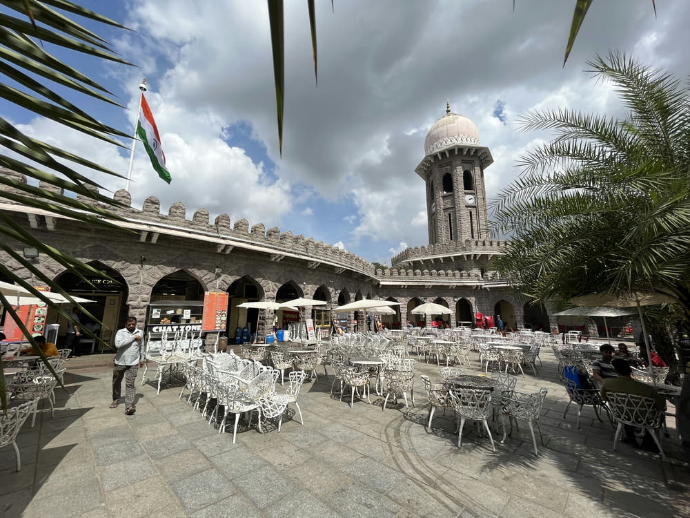 a courtyard with tables and chairs and a clock tower in the background