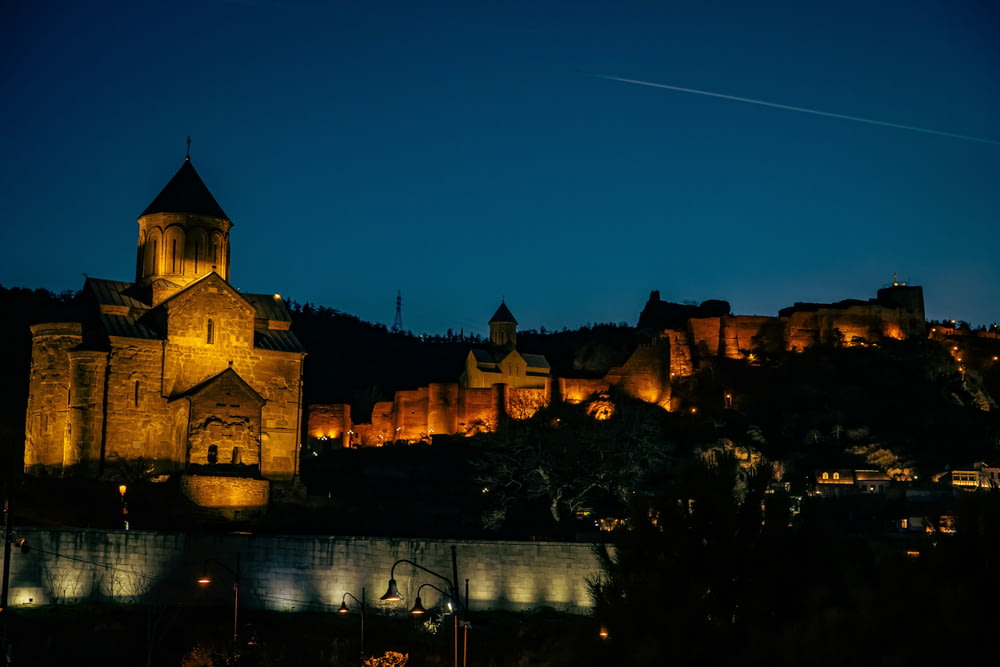 a castle lit up at night with a sky background