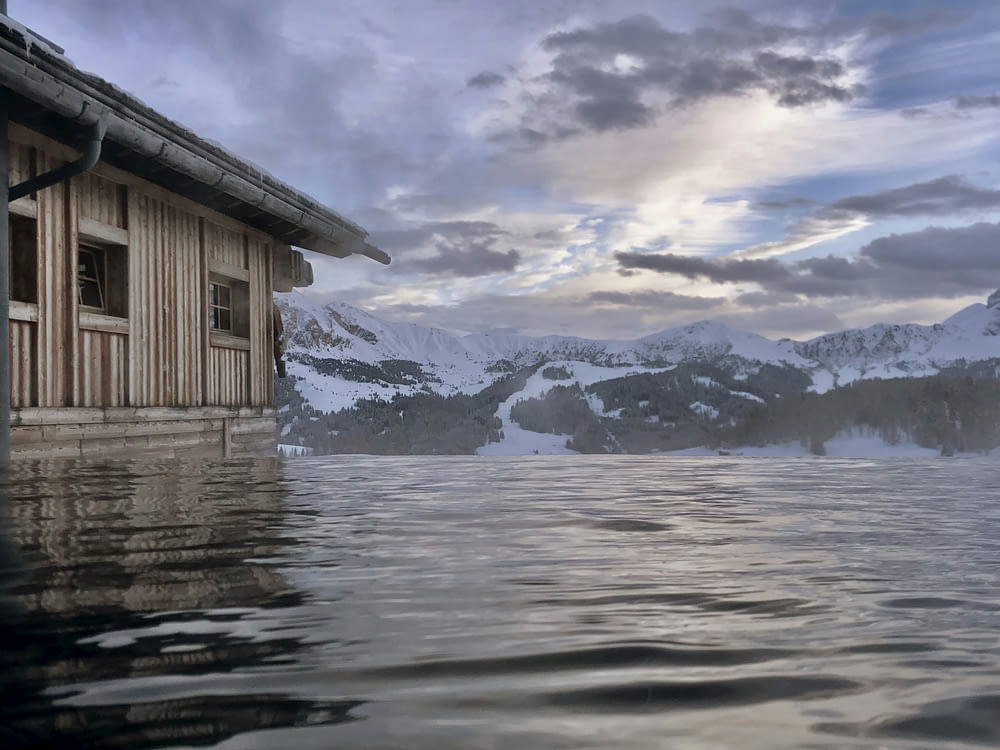 a house in the middle of a lake with mountains in the background
