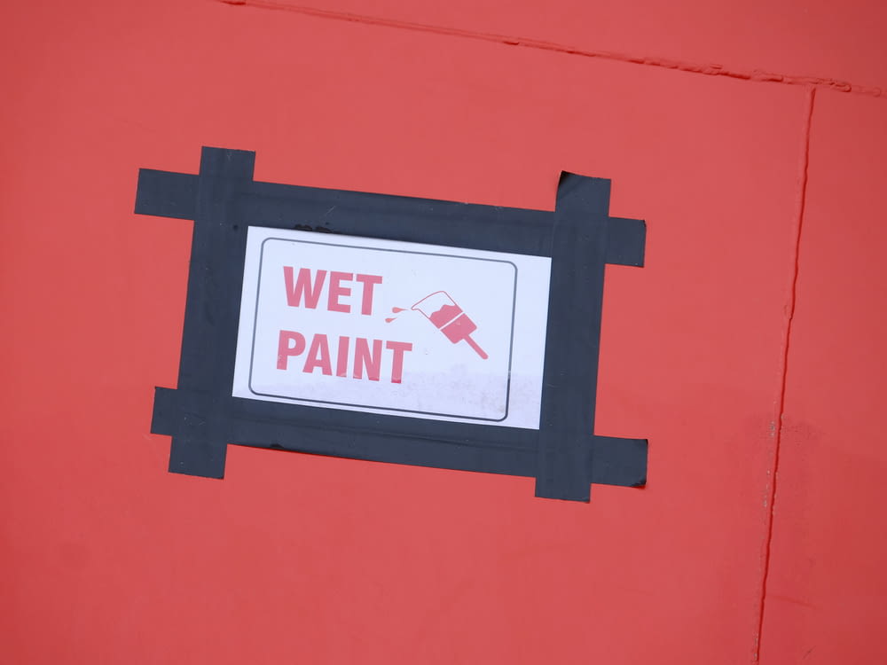 uma parede vermelha com uma placa que diz tinta molhada