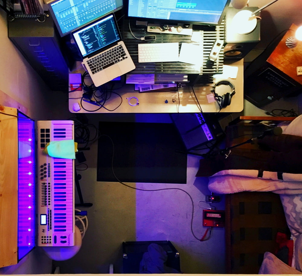 a desk with a laptop, keyboard, and two monitors