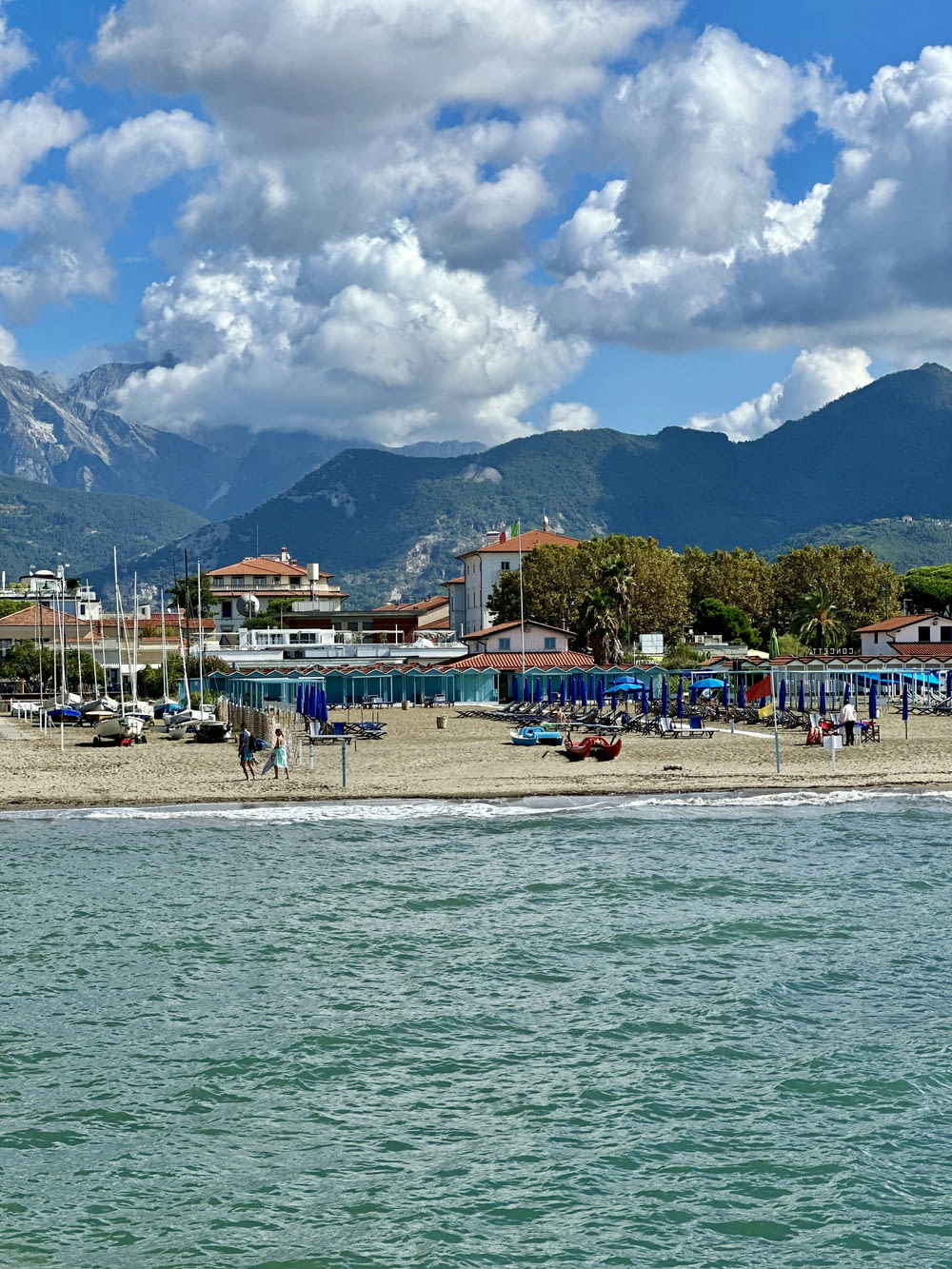 a beach with boats and mountains in the background