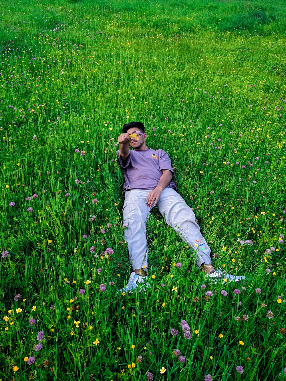 a man laying in the middle of a field of flowers