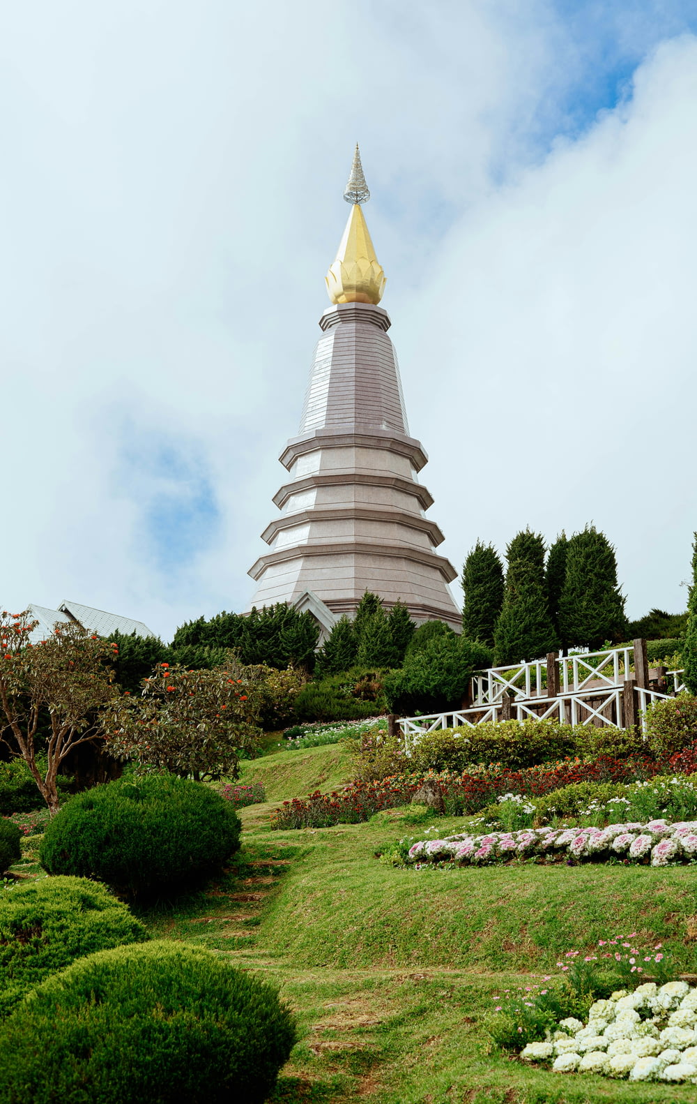 a very tall tower with a gold top in the middle of a garden