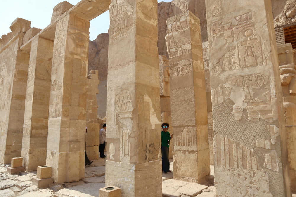 un hombre de pie entre dos grandes pilares de piedra