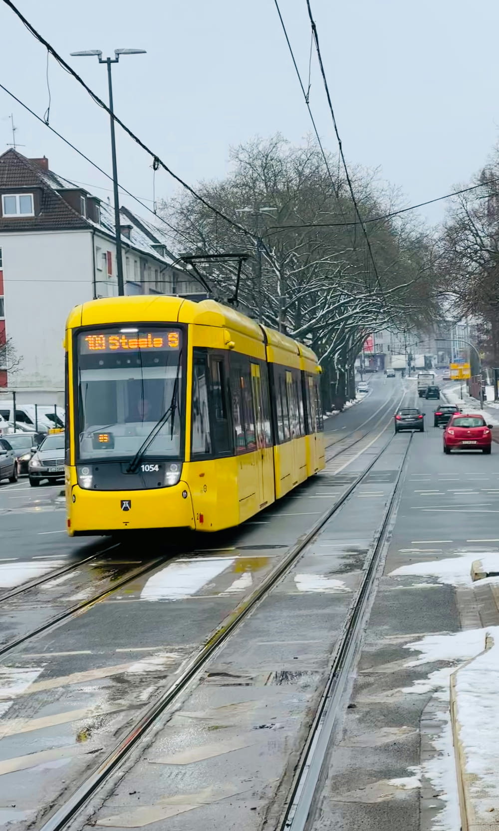 a yellow train traveling down a snow covered street