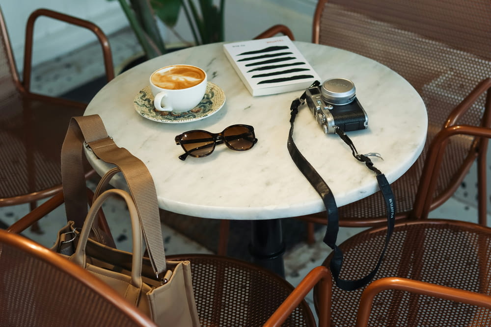 a white table topped with a cup of coffee and a camera