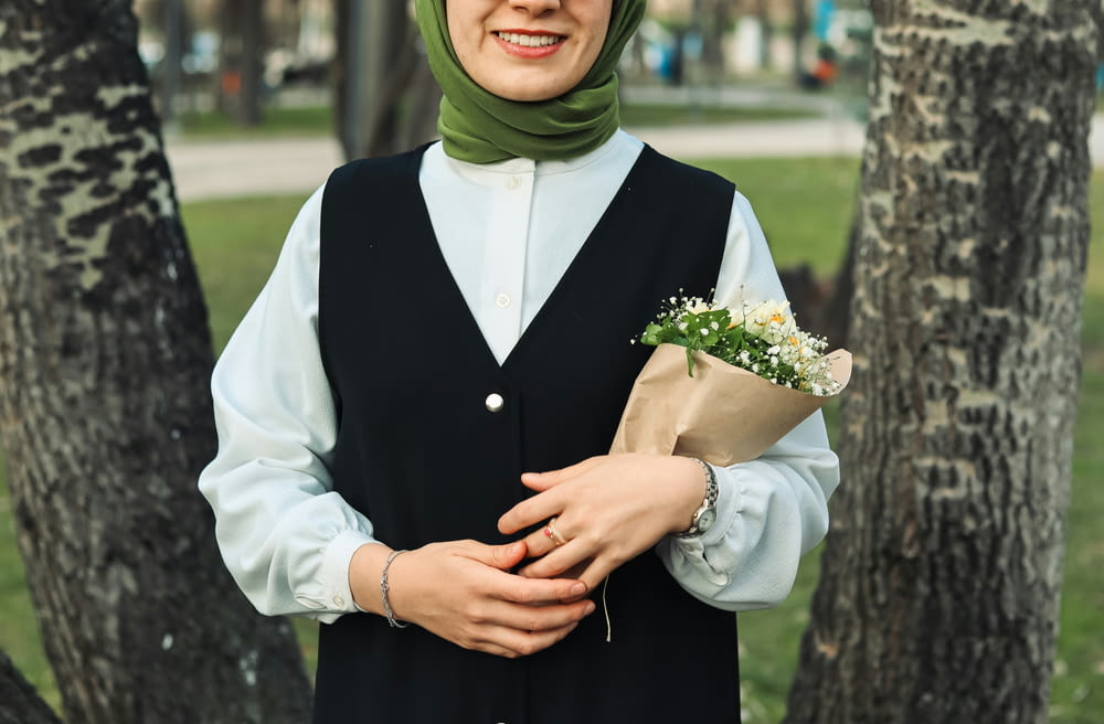 a woman in a hijab holding a bouquet of flowers