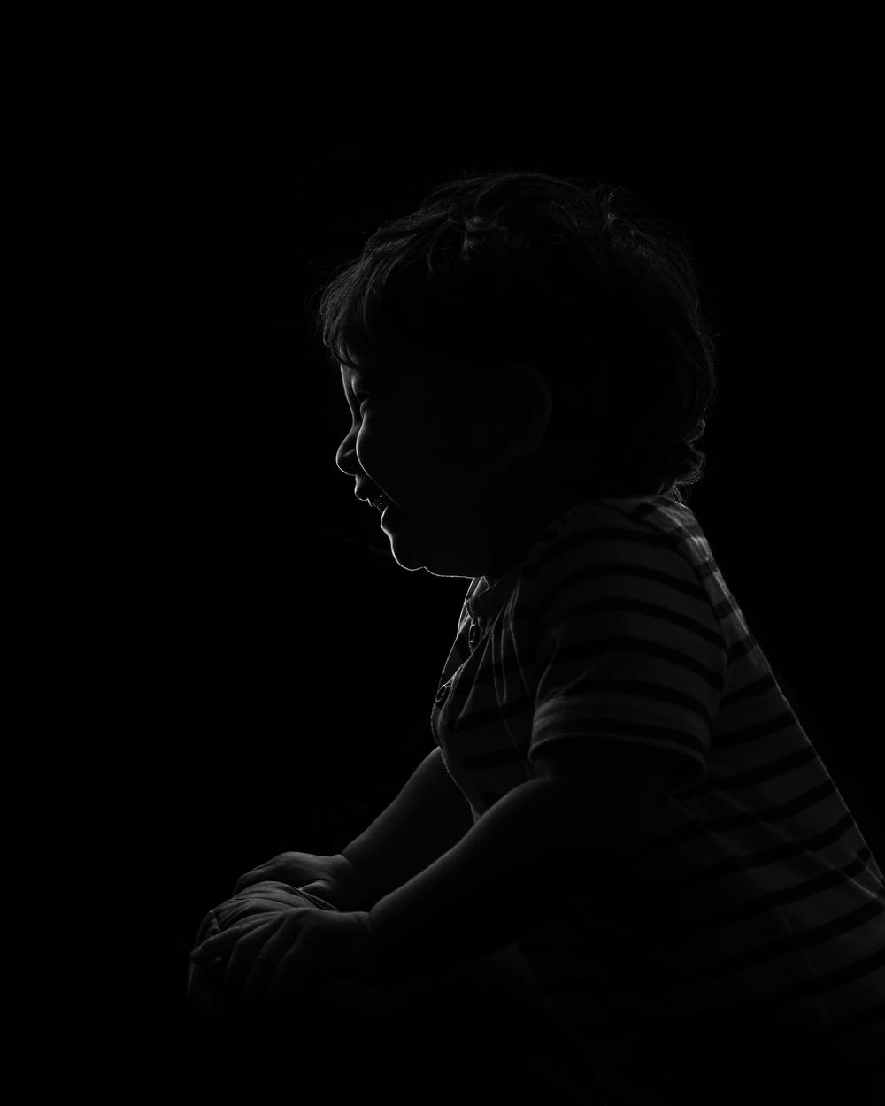 a little boy sitting down in the dark
