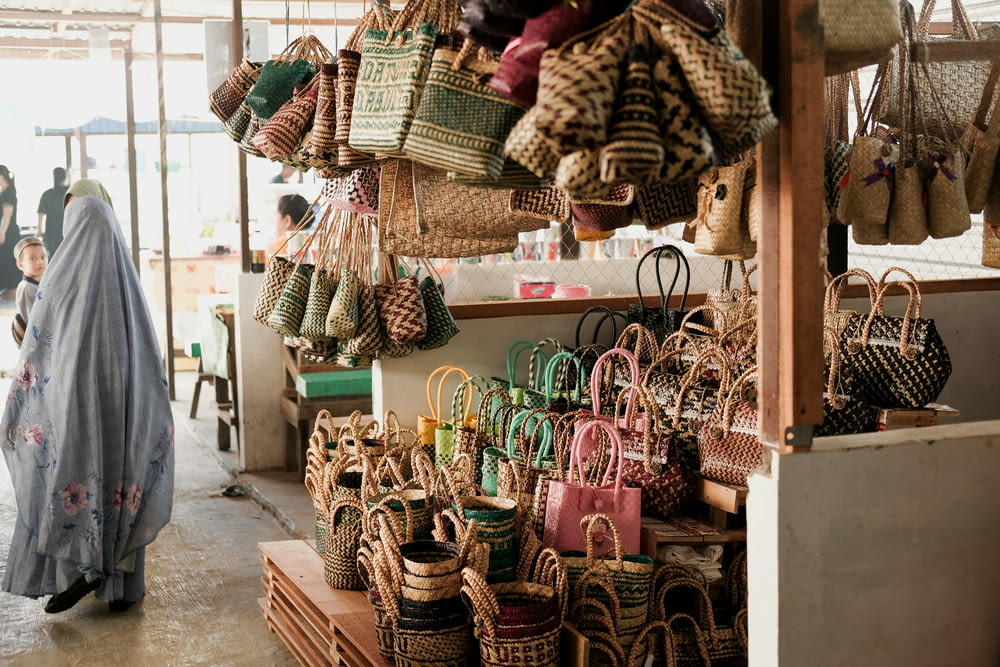 a woman standing in front of a store filled with baskets