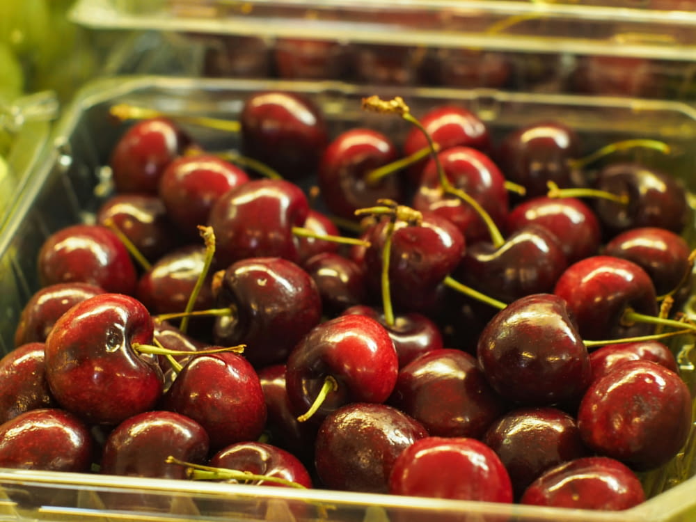 a plastic container filled with lots of cherries
