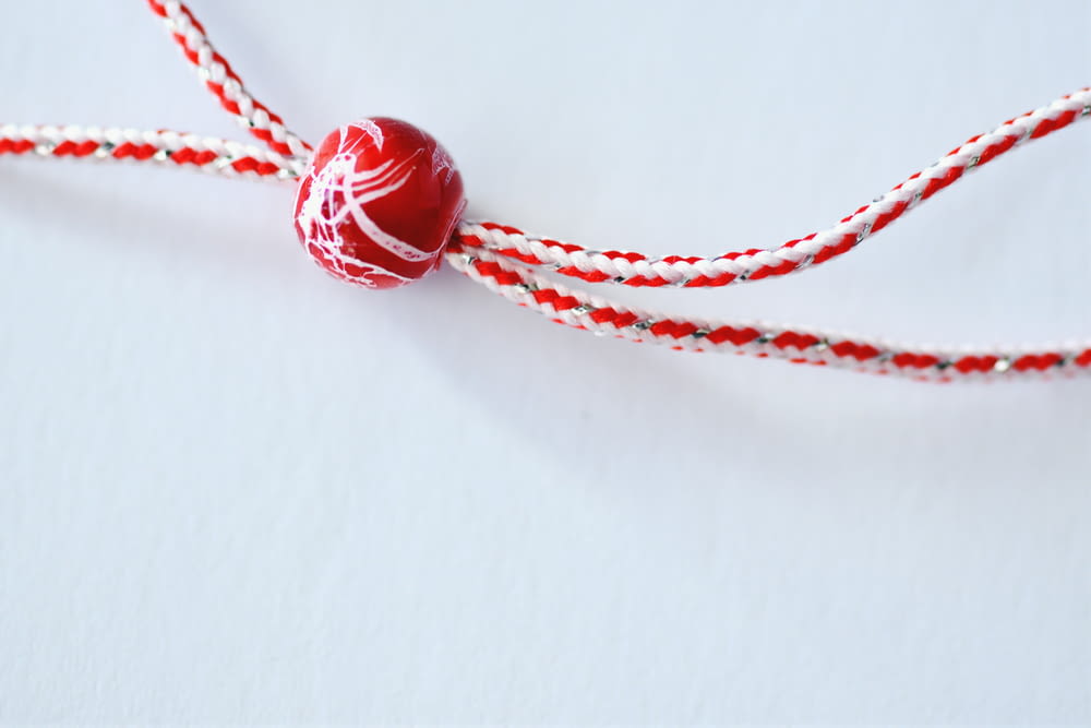 a red and white string with a red and white ball on it