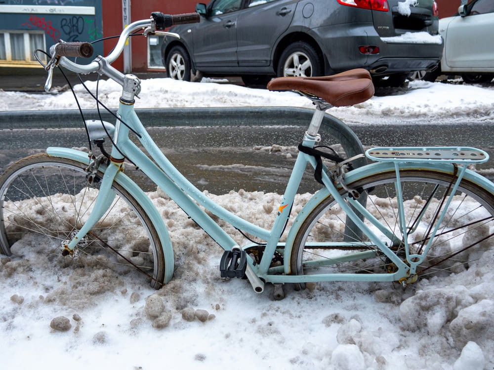 a blue bicycle parked on the side of a road covered in snow