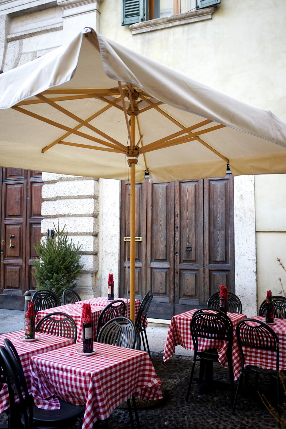 a table with a red and white checkered tablecloth under an umbrella